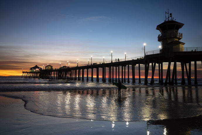 Silhouette of surfer at Huntington Beach Pier at sunset, California, USA