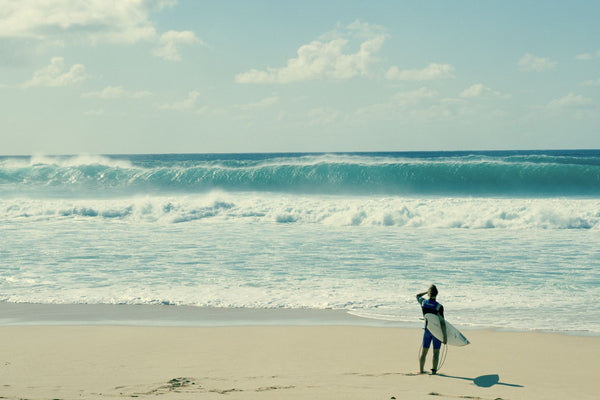 Surfer standing on the beach, North Shore, Oahu, Hawaii, USA