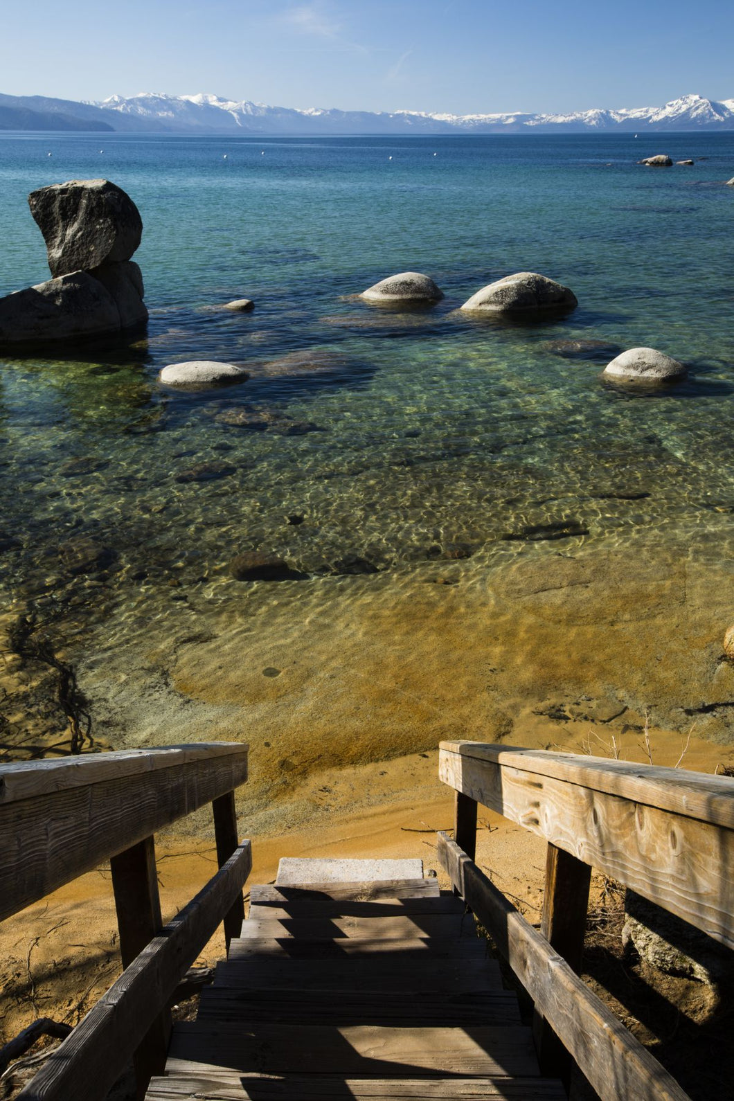 Rocks in a lake with mountain range in the background, Lake Tahoe, California, USA