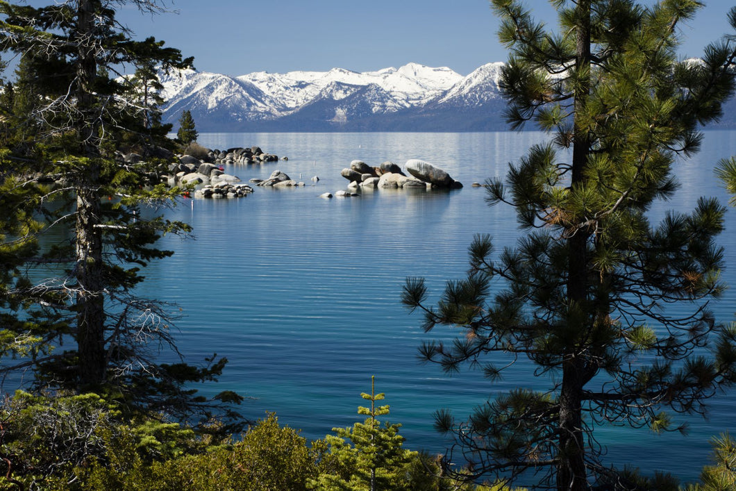 Rocks in a lake with mountain range in the background, Lake Tahoe, California, USA