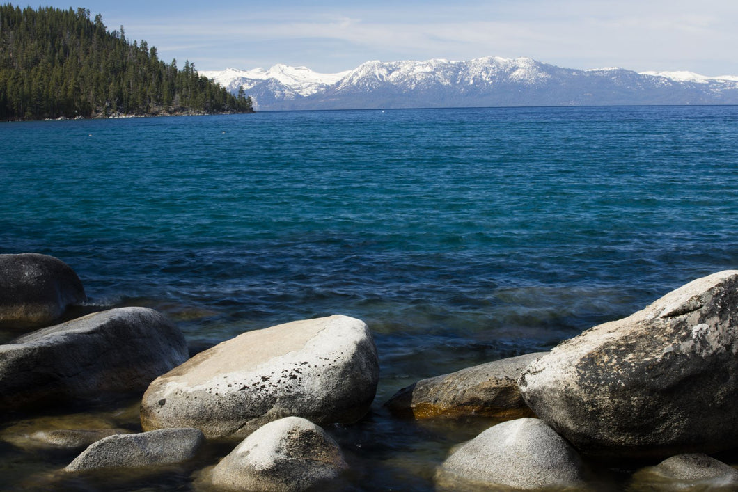 Rocks in a lake with mountain range in the background, Lake Tahoe, California, USA