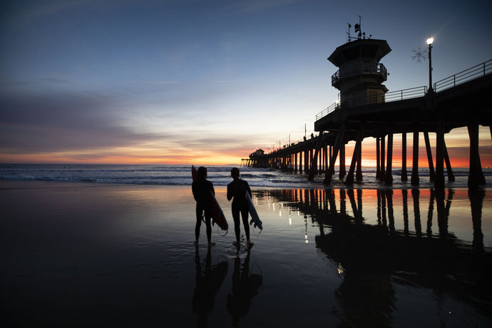 Silhouettes of surfers at Huntington Beach Pier at sunset, California, USA