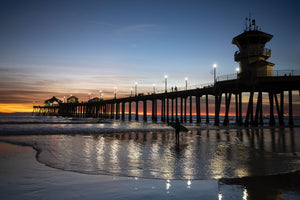 Silhouette of surfer at Huntington Beach Pier at sunset, California, USA