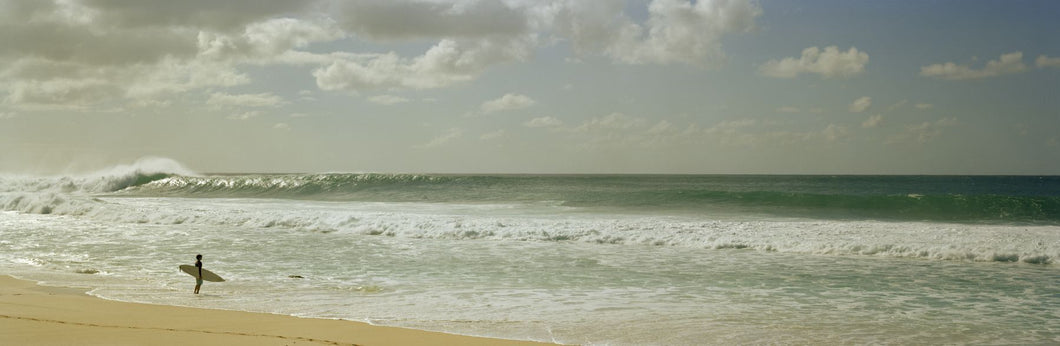 Surfer standing on the beach, North Shore, Oahu, Hawaii, USA