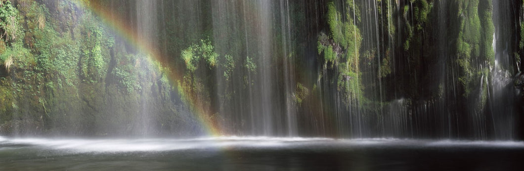 Rainbow formed in front of waterfall in a forest, near Dunsmuir, California, USA