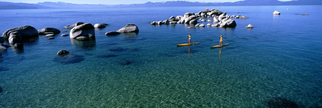 Two women paddle boarding in a lake, Lake Tahoe, California, USA