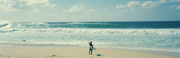 Surfer standing on the beach, North Shore, Oahu, Hawaii, USA