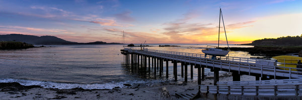 Pier and sailboat at sunset on Stillwater Cove, Pebble Beach, California, USA