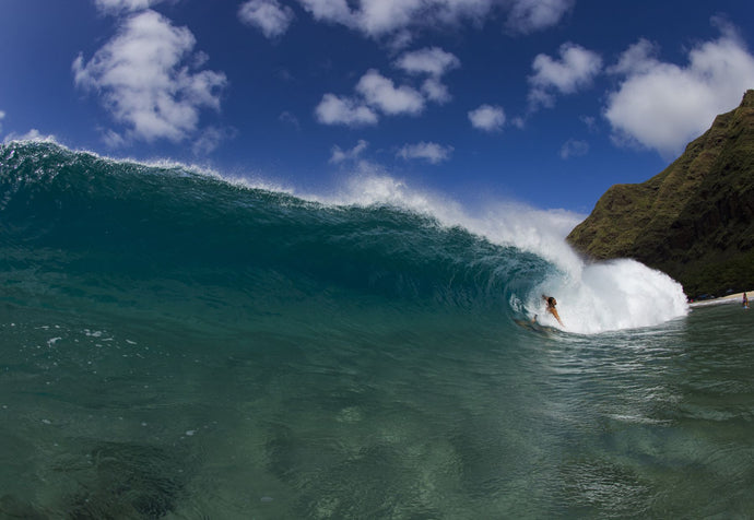 Surfer falling off into breaking wave on beach, Hawaii, USA