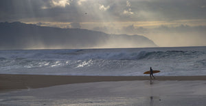 Surfer walking on the beach, Hawaii, USA