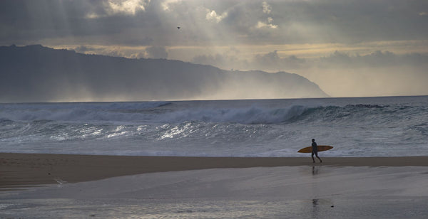 Surfer walking on the beach, Hawaii, USA