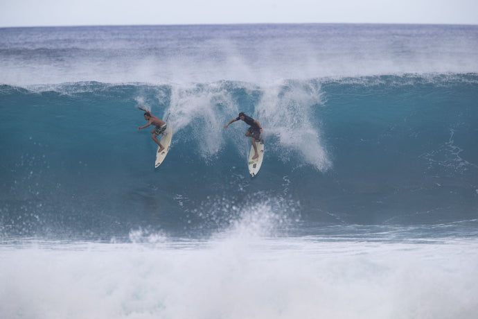 Surfers surfing down a wave on beach, Hawaii, USA
